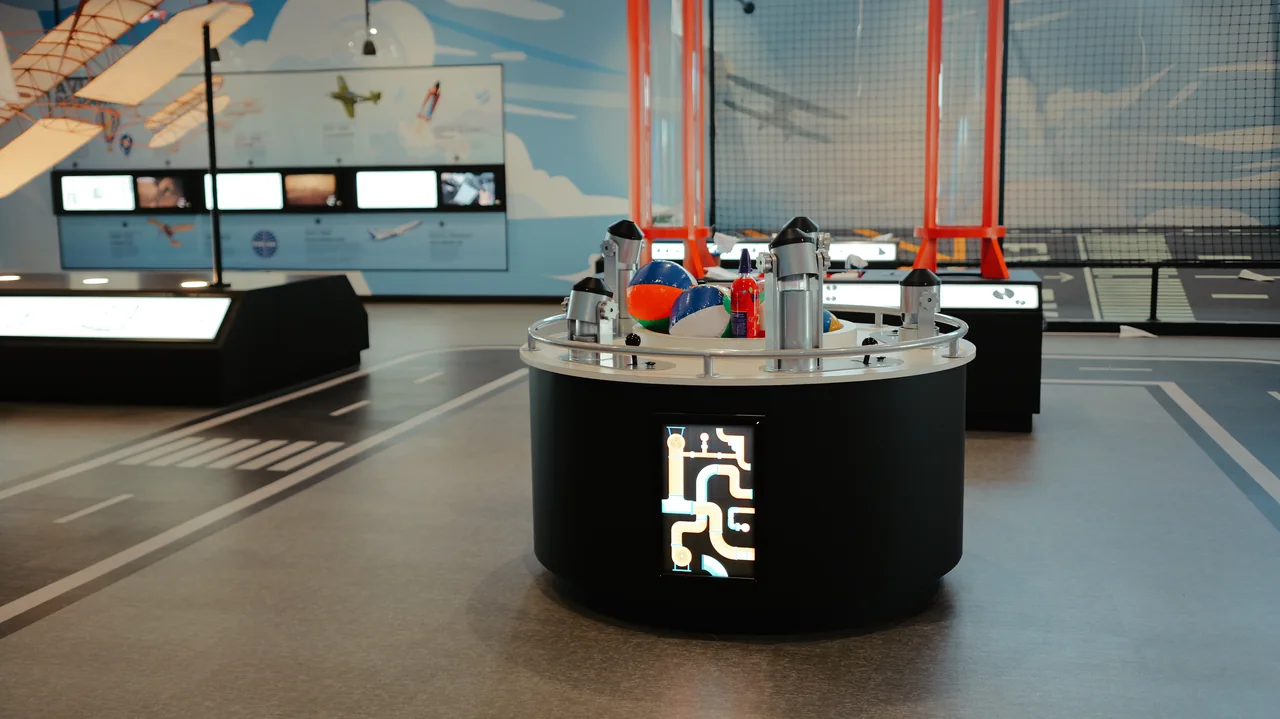A hands-on experiment station sits beneath suspended airplane models.